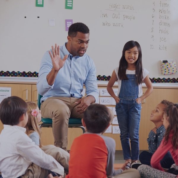 girl standing up in class next to the teacher